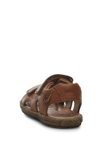 Brązowe skórzane sandały o otwartym wzorze, z regulowanym paskiem, teksturowaną podeszwą i wycięciami dla wentylacji. Zawierają okrąły akcent logo.