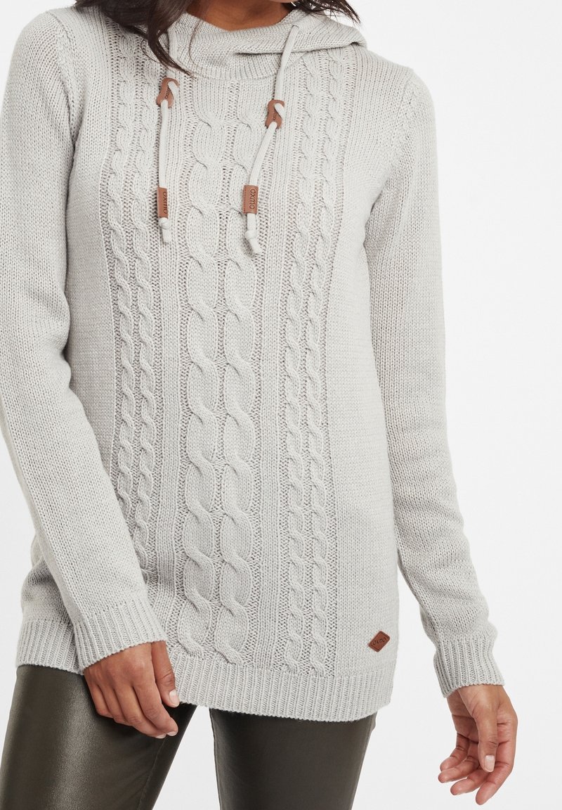Light gray knit sweater with cable patterns, a high neckline, and adjustable drawstrings. Features ribbed cuffs and a small logo tag.
