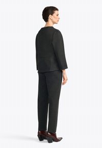 Zwart gebreid outfit bestaande uit een gestructureerde top met driekwart mouwen en slanke broek, gecombineerd met hakken met puntige neuzen.
