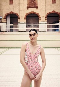 Pink floral swimsuit with a deep V-neck and thin straps, featuring a mix of small flower patterns on soft fabric.