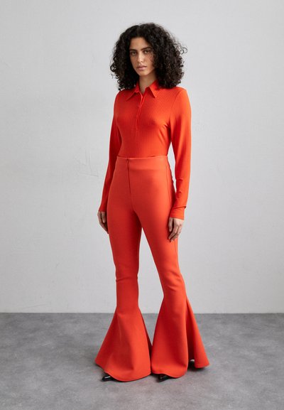Red ribbed long-sleeve shirt with button placket and matching flared pants, featuring a smooth texture and a fitted silhouette.