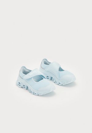 Light blue sneakers with mesh fabric, prominent cut-outs in the sole, and a Velcro strap across the top for secure fit.