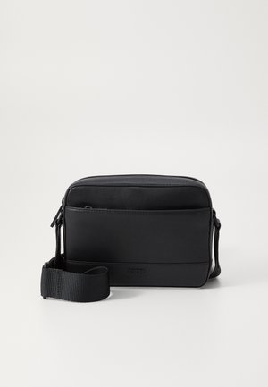 Black messenger bag made of smooth leather featuring a front pocket, zip closure, and adjustable fabric strap. Brand logo embossed on the front.