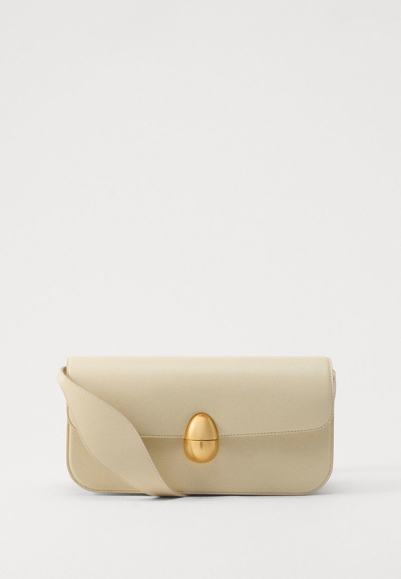 Beige leather handbag with a smooth texture, rectangular shape, and a golden oval clasp. Features a long, adjustable strap.