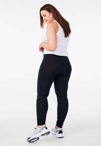 Mustad retuusid sujuva tekstuuriga, valge toppiga ühendatud. Komplekti täiustavad valged ja mustad sportlikud kingad.