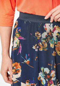 Bloemrok met een marineblauwe basis, voorzien van levendige bloemenpatronen in oranje, roze en groen. Rekbare tailleband, ademende stof.