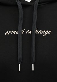 Sweat à capuche noir avec de grosses cordelettes noires et logo "armani exchange" blanc en écriture cursive brodé sur la poitrine.