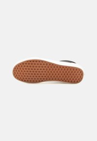 Shoe sole with a textured brown rubber design featuring a diamond pattern, bordered by a white midsole with a smooth finish.