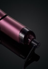 Sèche-cheveux compact en métal violet profond avec une finition mate. Il dispose d'un câble texturé noir et d'un embout circulaire brillant avec des accents ventilés.
