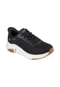 Zapatilla deportiva negra con parte superior de malla, cierre de cordones, entresuela blanca y suela de goma texturizada marrón. Presenta una marca en el costado.