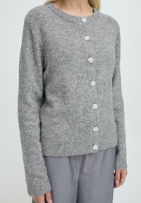 Grauer Wollcardigan mit langen Ärmeln, Rundhalsausschnitt und fünf verzierten Knöpfen an der Vorderseite. Verfügt über gerippte Bündchen und Saum.