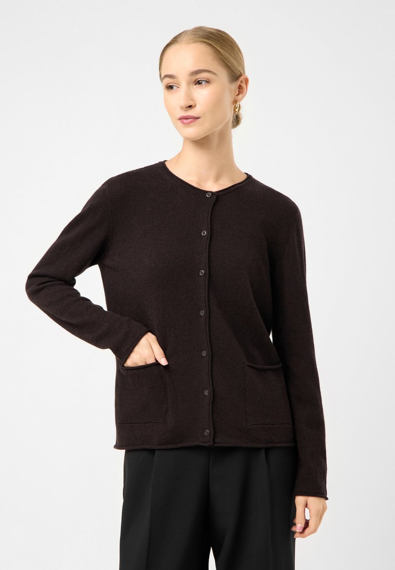 Dunkelbrauner Cardigan aus weichem Material mit rundem Ausschnitt, vorderem Knopfverschluss und zwei Fronttaschen. Lange Ärmel sind enthalten.