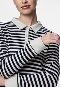 Tamsiai mėlynas ir baltas dryžuotas ilgomis rankovėmis polo marškinėliai su pilku apykakle ir mygtukų užsegimu, pasižymintys ribota tekstūra ir kontrastingais rankogaliais.