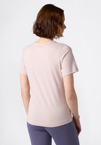 T-shirt di cotone rosa chiaro con maniche corte e scollatura rotonda, abbinato a pantaloni viola scuro. Tessuto liscio e design semplice.