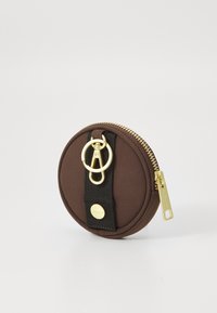 Runder, brauner Stoffmünzbeutel mit goldfarbenem Reißverschluss, ausgestattet mit einem schwarzen Trageband und goldfarbener Hardware für eine einfache Befestigung. Glatte Textur und schlichtes Design.
