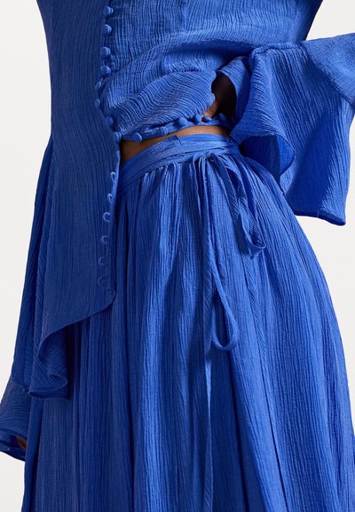 Blauw getextureerd twee-delig outfit met een losse blouse met knoopaccenten en een vloeiende rok met een gestrikt tailleband en geplooid ontwerp.