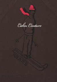 Brązowy sweter z haftowanym wzorem narciarza. Narciarz ma na sobie czerwony kapelusz i szalik, a na dole znajduje się napis "Pockies".