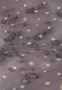 Tissu foncé avec de petits motifs d'étoiles dorées et des gouttes d'eau dispersées sur la surface.