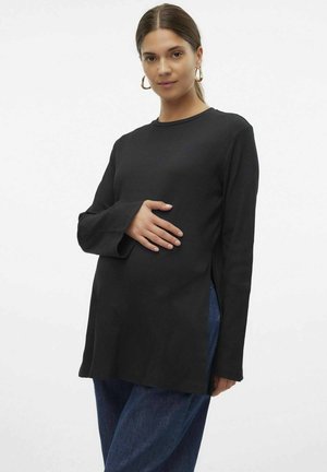 Svart ribbad långärmad topp med sidoflikar, rund halsringning och avslappnad passform, tillsammans med blå denimbyxor.