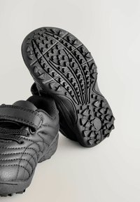 Zwarte sportieve schoenen met gestructureerde rubberen zolen. Voorzien van een klittenbandsluiting en een synthetisch bovenwerk met subtiele stikseldetails.