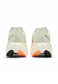 Light beige and white athletic shoes feature a textured mesh upper, contrasting black and orange soles, and a sleek, supportive design.