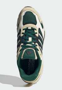 Sneaker vert et crème en mesh et daim, avec des rayures noires, un col rembourré et l'étiquette 'Cloudfoam Comfort' à l'intérieur.