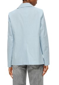 Blazer su misura di un blu chiaro con una singola apertura, colletto a risvolto e una texture liscia, abbinato a pantaloni in denim grigi.
