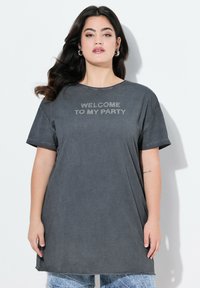 Grå oversized t-shirt med korte ærmer og teksten "VELKOMMEN TIL MIN FEST" i rhinsten. Blødt stof og afslappet pasform.