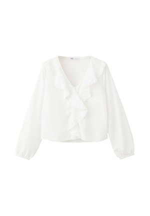 Blouse blanche à manches longues avec col en V et détail volanté sur le devant, poignets élastiques et coupe légèrement courte sur un fond uni.