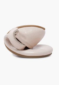 Béžová zakřivená nazouvací obuv s lesklým pateňovým povrchem, texturovaným páskem a flexibilní gumovou podrážkou. Dekorována suchým zipem.