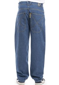 Modri traper hlače z ohlapnim krojem, ki imajo zadnje žepe z značilnim križastim šivanjem in vidno barvno črtasto oznako.