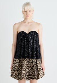 Abito senza spalline con un corpino di paillettes nere e una gonna a stampa leopardata. La gonna ha plissettature e una texture lucida e liscia.