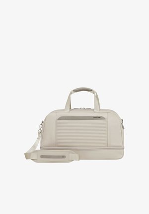 Beige, weich strukturierte Reisetasche mit horizontalen Rillen an der Vordertasche, zwei Griffen, abnehmbarem, gepolstertem Schultergurt und Reißverschlussverschlüssen.