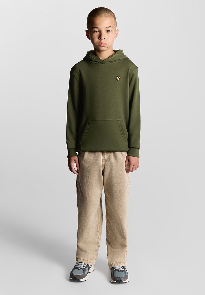 Felpa con cappuccio verde oliva con tasca frontale e logo, abbinata a pantaloni cargo beige e sneakers grigie con dettagli blu.