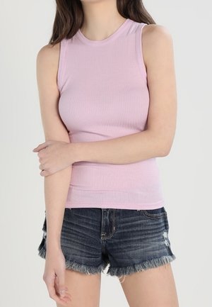 Rosa geripptes ärmelloses Oberteil kombiniert mit ausgefransten Jeansshorts, die leichte Used-Effekte und ein klassisches Fünf-Taschen-Design aufweisen.