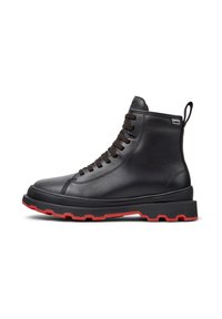 Stivale alto in pelle nera con lacci neri, suola spessa nera con battistrada rosso, linguetta sul tallone e piccolo etichetta Camper Hydroshield.