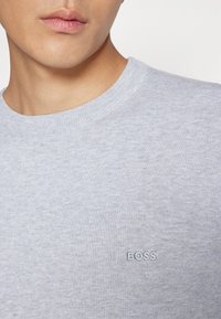 Ljusgrå crewneck-tröja i mjukt material med en diskret "BOSS"-logotyp broderad i en kontrasterande nyans.