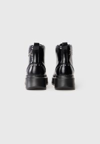 Pair of black leather ankle boots with studs and pull tabs, viewed from the back on a plain white background.
