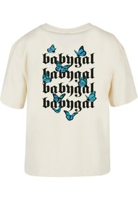 Kremfarget t-skjorte med svart gotisk tekst "babygal" gjentatt fire ganger og blå sommerfugler spredt rundt teksten på baksiden.