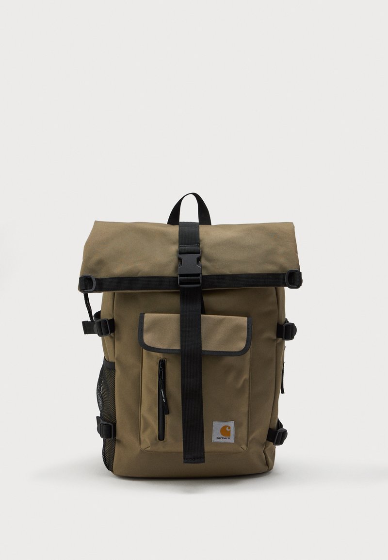 Mochila de rollo color caqui con correa de hebilla negra, bolsillo frontal con cremallera, bolsillo lateral de malla y parche con el logo de Carhartt en la parte inferior derecha.