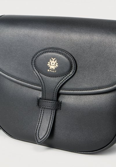 Μαύρη δερμάτινη τσάντα χειρός Bally με κλείσιμο με καπάκι, ραμμένο λουράκι και χρυσό ανάγλυφο λογότυπο στη μέση μπροστά.