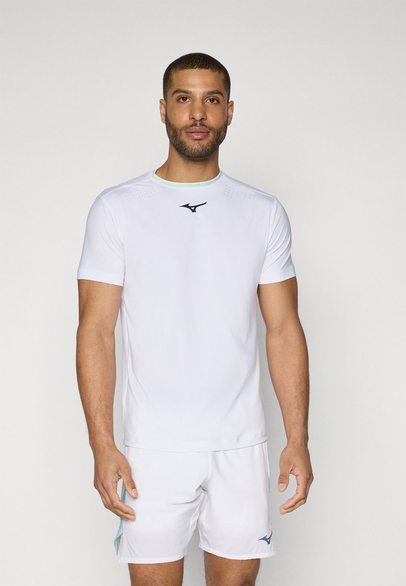 Camiseta deportiva blanca de manga corta, con un logotipo negro en el pecho y sutile perforaciones cerca de los hombros.