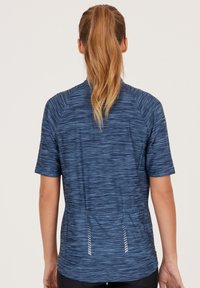 Herrtröja för träning i lätt, fukttransporterande material. Har ett blått, texturerat mönster med korta ärmar och sidsprund.