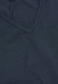Marineblå V-hals T-shirt lavet af blødt, glat bomuldsstof med et simpelt design og synlige sømme langs kraven og kanten.