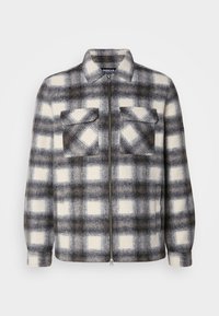 Plaid jacket in gray and off-white, made from soft fabric. Features two chest pockets and a zip front with a collared neckline.