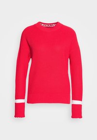Pull en laine rouge avec un col montant, texture côtelée et rayures blanches sur les manches. Coupe ample et design avec des épaules tombantes.
