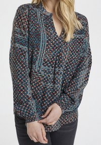 Bluzka z długim rękawem z przezroczystego materiału, ozdobiona kwiatowym wzorem w kolorze niebieskim, czerwonym i beżowym, z dekoltem w serek i marszczonymi mankietami.