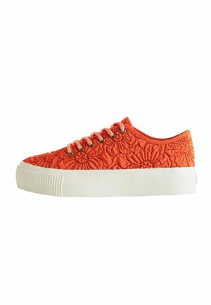 Zapatilla baja con tejido acolchado floral naranja, suela de plataforma blanca y cordones naranjas a juego con ojales metálicos.
