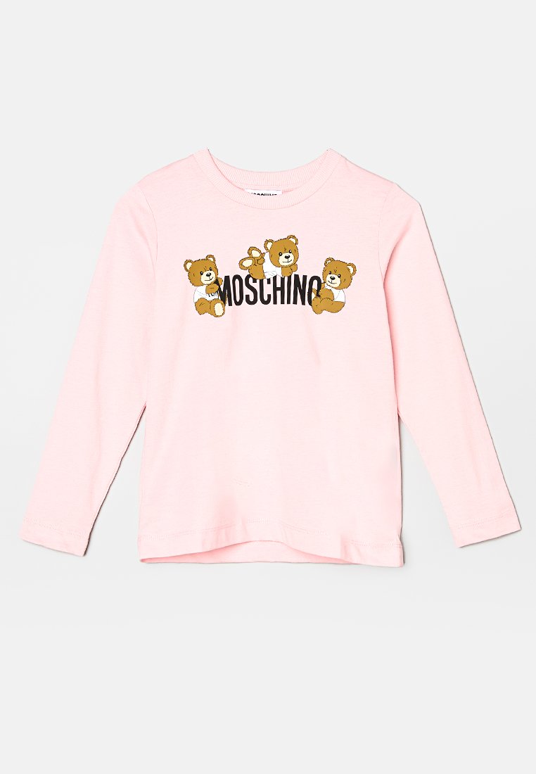 Chemise à manches longues rose clair ornée de trois ours en cartoon et du logo "Moschino" en lettres noires en gras. Matériau en coton doux, coupe classique.