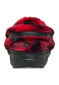 Rode en zwarte met bont gevoerde klompen met een zwarte rubberen zool. Bevat een zwarte band met het "crocs" logo en een gestructureerde basis voor grip.